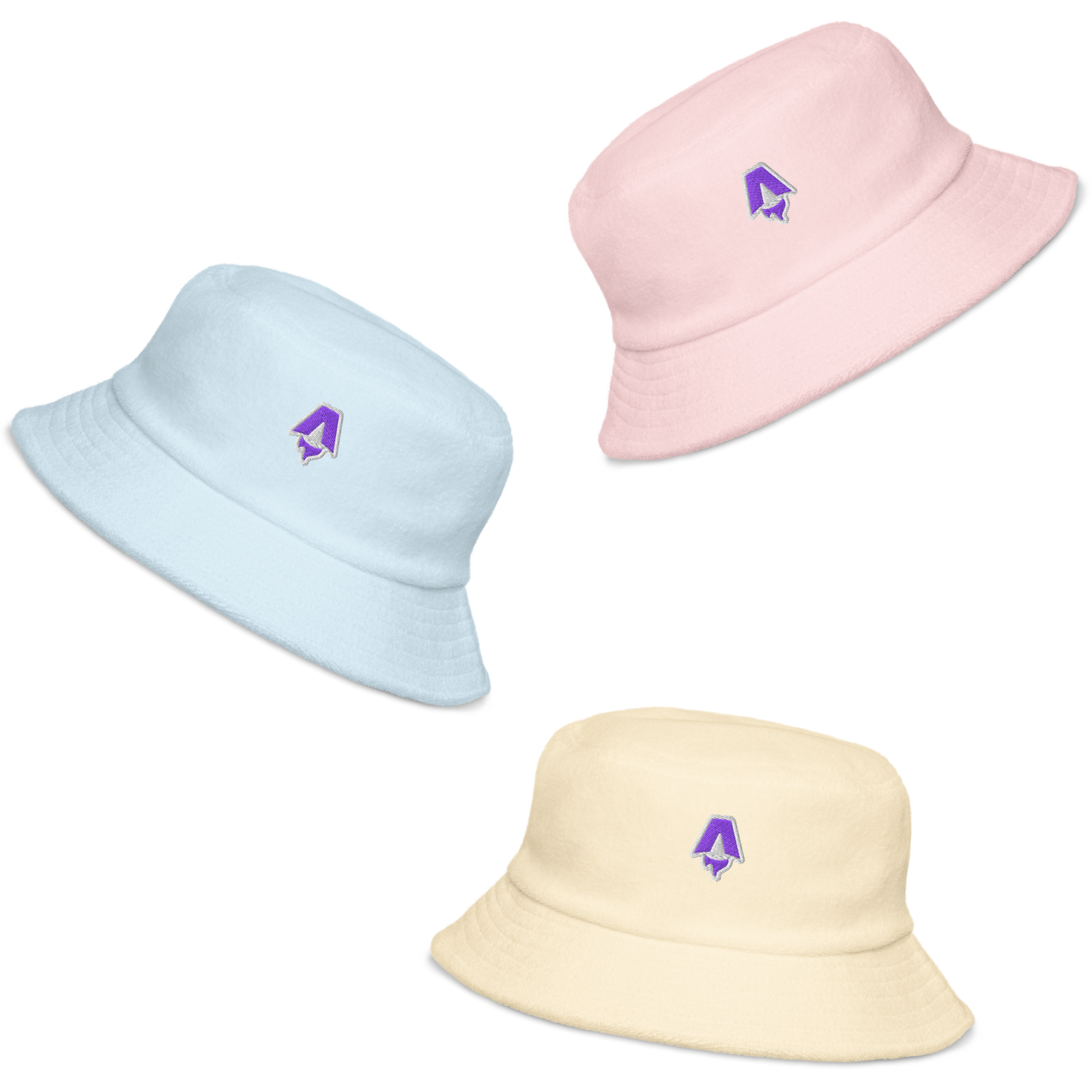 Three bucket hats each of a different pastel shade: light pink, light blue, and light yellow. Each hat has an embroidered patch on the front of the Astro logo in purple and white.